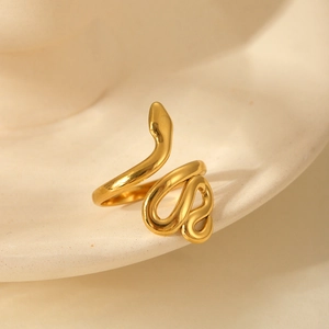 Vue macro de la bague serpent dorée sur céramique montrant sa texture polie élégante