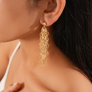 Détail de boucles d'oreilles dorées avec anneaux dépolis et clou en zircon brillant