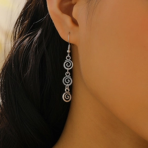 Gros plan de boucles d'oreilles spirales argentées sur un mannequin aux détails raffinés