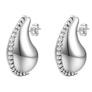 Macro detail of silver teardrop hollow earrings with inlaid white zircons on polished steel