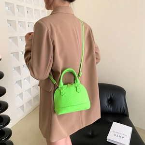 Neon green shell-shaped mini crossbody bag with animal texture on a fashion model