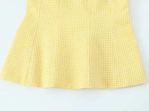 Detailaufnahme der gelb-weißen Gingham-Seersucker-Textur und des Rüschensaums am Saum
