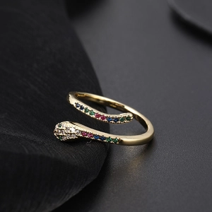 Macro close-up of gold snake ring with sparkling colorful zircon stones on black background