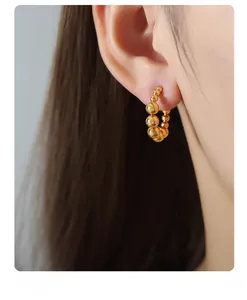 Detail of beaded hoop earring in 18k gold plated steel on model for a retro vintage style