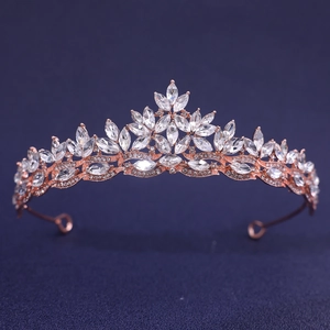 Detail of rose gold bridal tiara with leaf-shaped crystals on dark blue background