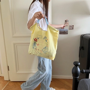 Détail d'un cabas jaune en tissu Oxford avec broderies florales et anses à carreaux