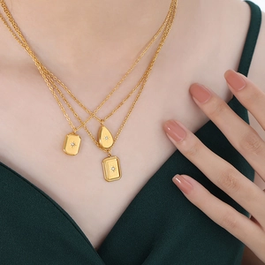 Three-layer gold pendant necklace with starburst engraved square and teardrop charms