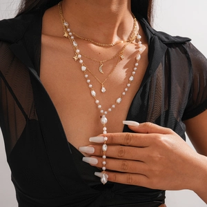 Detail of layered gold necklace with star, moon pendants and baroque pearls on model
