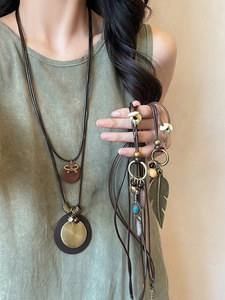 Detail of star feather fringe necklace with wooden disc and bohemian leather cord