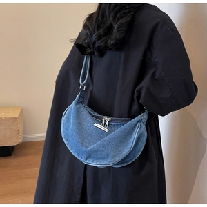 Detailed view of denim crescent bag with double metal zippers and fashion label