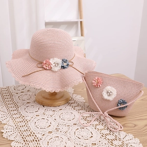 Détail d'un ensemble chapeau et sac en paille rose avec fleurs et perles décoratives