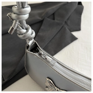 Detailed macro view of silver metallic bow accent and knotted strap on stylish handbag