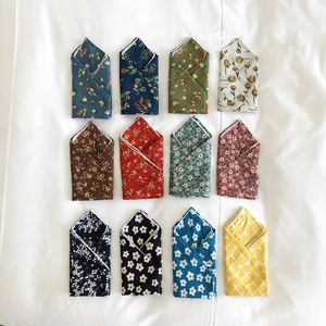 Flat lay of multiple folded cotton linen scarves with floral heart patterns in various colors