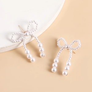 Detail of handmade bow knot faux pearl earrings with elegant cascading drop strands