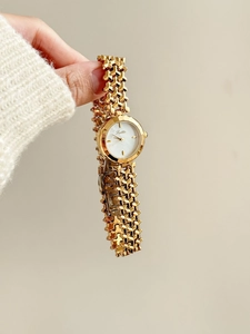 Dettaglio orologio vintage da donna dorato con quadrante in madreperla e cinturino a catena