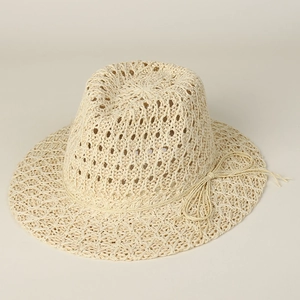 Detailed close-up of intricate hollow weave pattern and bow on cream straw sun hat