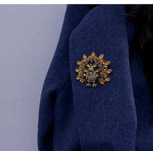 Detailed close-up of a vintage turkey brooch with colorful crystals on a navy wool coat