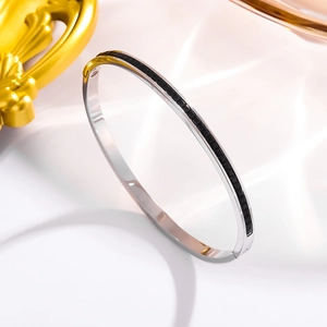 Close-up of polished stainless steel bangle with black rectangular stone inlays