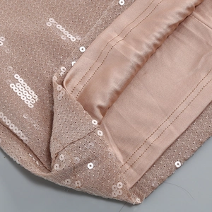 Detalle de lentejuelas doradas sobre tela de malla con forro interior suave y liso