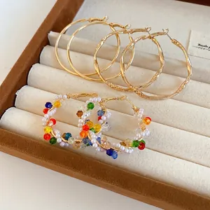 Vintage style gold hoop earring set with pearls and colorful crystals in a beige jewelry box