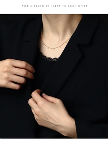 Detail of a minimalist gold-plated necklace with zircon beads worn with a black blazer