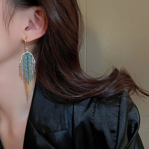 Macro shot of long tassel earrings with gradient blue to gold rhinestones on a model