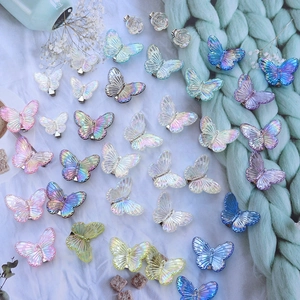 Flat lay of colorful gradient butterfly hair clips on mint green knit and dried flowers