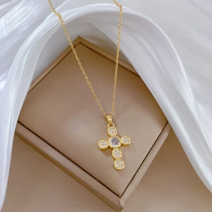 Detailed close-up of a gold cross pendant necklace with sparkling micro-pave zircons