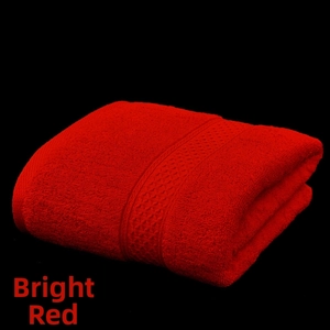 Close-up of red cotton bath towel with textured geometric border on black background