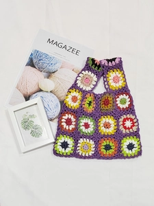 Macro shot of handmade crochet granny square bag with colorful floral knit patterns