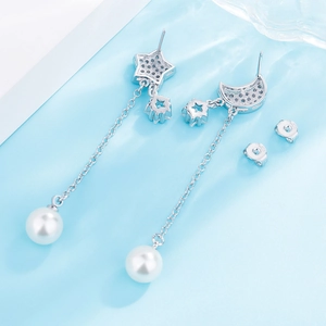Detail of S925 sterling silver star and moon earrings with white pearls on blue silk