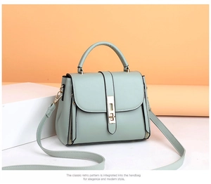 Detail of mint green leather handbag featuring a secure gold metal twist lock and handle
