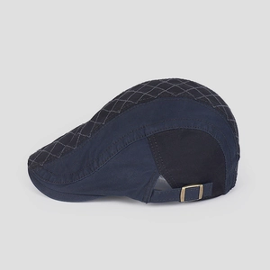 Detail of vintage navy cotton flat cap showing quilted grey top and brass metal buckle