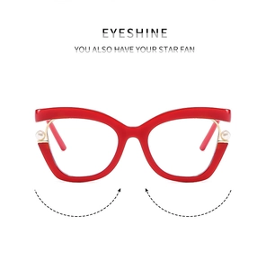 Detailed close-up of red cat-eye frames with elegant pearl and gold metal accents