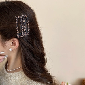 Dettaglio di fermagli per capelli rettangolari leopardati con eleganti gioielli di perle