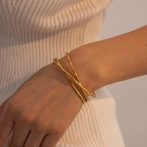Primer plano de un brazalete multicapa de acero inoxidable chapado en oro en la muñeca