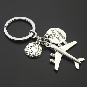 Macro view of silver travel keychain with airplane globe and no matter where engraving