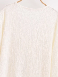 Detailed macro view of white textured fabric and shoulder seam on a lightweight summer top