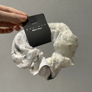 Detailed shot of white floral lace scrunchie featuring a detachable bow and brand tag