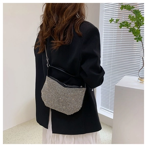 Close-up of sparkling silver rhinestone handbag with black strap on a model's shoulder