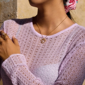 Close-up of 18K gold heart necklace with twisted texture and crystal on model