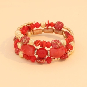 Detailed close-up of bohemian multilayer beaded bracelet with red stones and gold charms