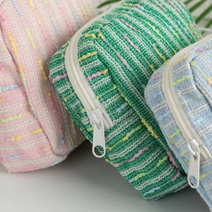 Close-up of pastel tweed textured cosmetic bags with zipper detail in colorful weave