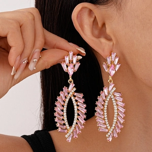 Elegant gold earrings with pink gemstones and dangling tassels on a female model