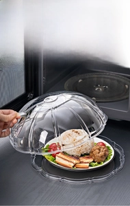 Transparent microwave plate cover with steam vent and handle over a dish of food