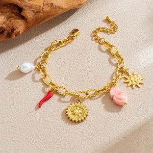Bracelet en acier doré avec breloques soleil, perle et piment sur fond beige texturé