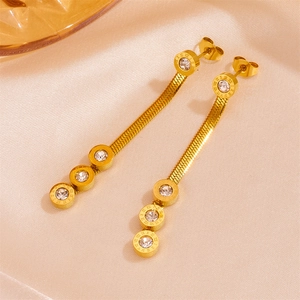 Vue détaillée des boucles d'oreilles serpent dorées avec chiffres romains sur soie satinée