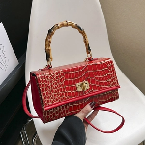 Close-up of red crocodile embossed leather handbag with natural bamboo handle and metal lock