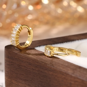 Close-up of gold S925 silver hoop earrings with baguette-cut zircon on a jewelry box