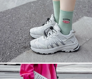 Close-up of white mesh sports sneakers with silver reflective strips on outdoor steps